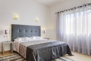A bedroom with a large bed, two bedside tables, a headboard, and a window with sheer curtains. - Lourenço - Amazing Villa with private pool, air/con, BBQ, Free Wi-Fi, near amenities (Albufeira)