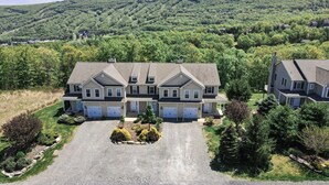 A large, multi-story house with a spacious driveway and a well-maintained lawn. - ⭐️ Spacious Mountaintop Oasis at Camelback | 2,500 SF w/ Game Room, Deck & A/C (Tannersville)