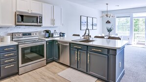 A modern kitchen with stainless steel appliances, grey cabinets, and a large island. - ⭐️ Spacious Mountaintop Oasis at Camelback | 2,500 SF w/ Game Room, Deck & A/C (Tannersville)