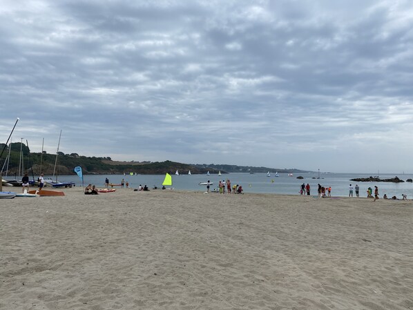 Una playa con barcos, gente y una bandera.