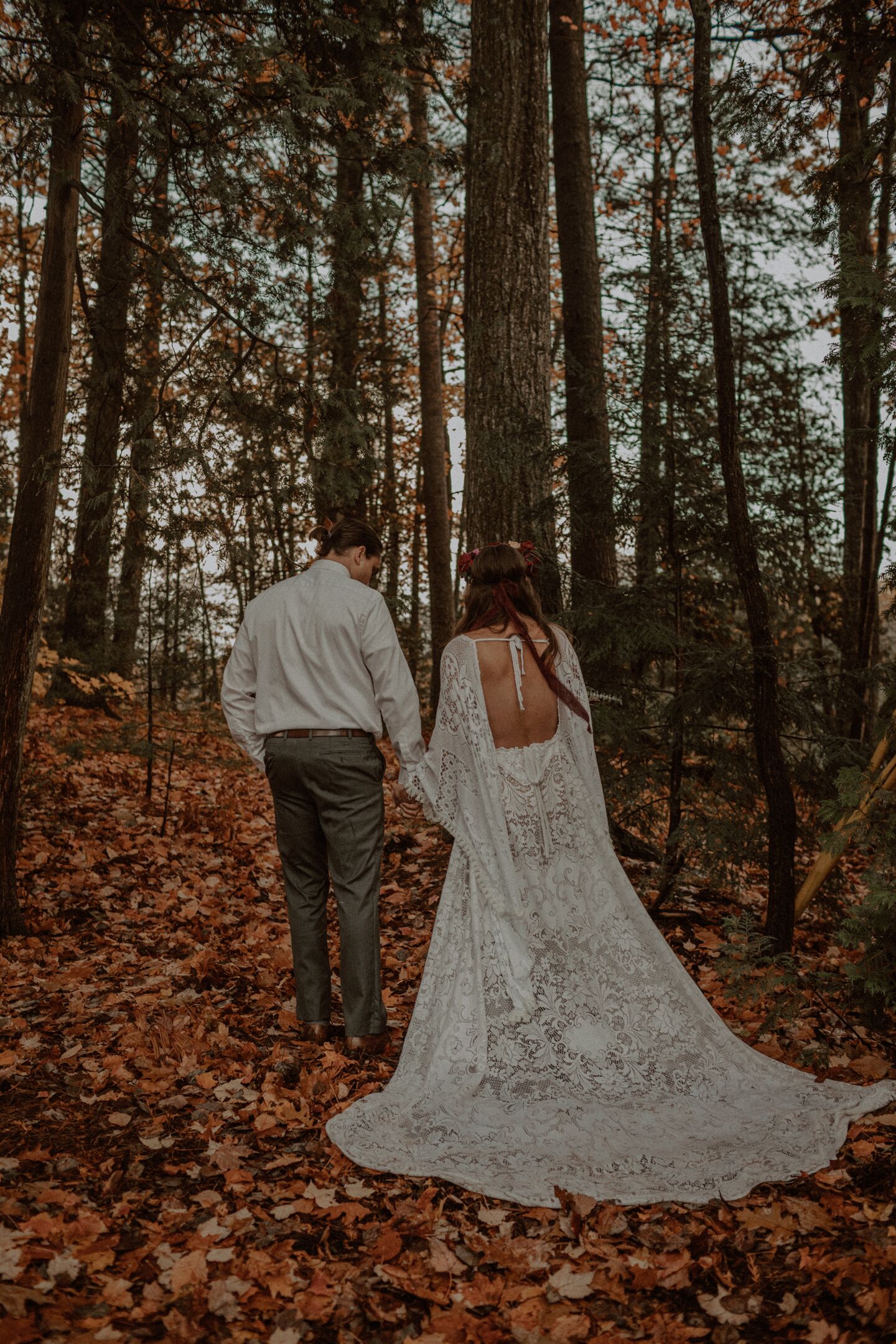 Una pareja caminando por un bosque con un sendero cubierto de hojas caídas.