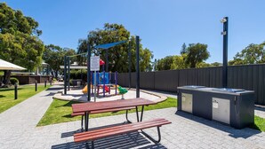 A playground with a slide, swings, and a picnic table. - FiftyTwo @ Cape View is the perfect family or couples getaway accommodation (BROADWATER)