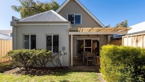 A single-story house with a covered patio, a small garden, and a wooden fence. - FiftyTwo @ Cape View is the perfect family or couples getaway accommodation (BROADWATER)