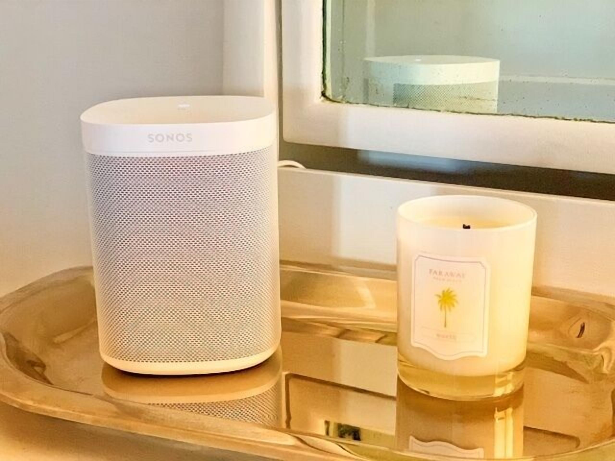 A SONOS speaker and a FARAVAL candle on a tray by a window.