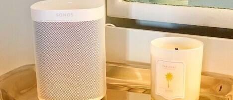A SONOS speaker and a FARAVAL candle on a tray by a window.