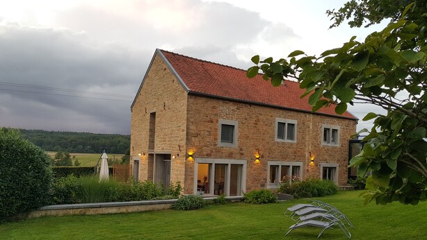 A stone house with a red roof, a well-maintained lawn, and outdoor seating. - Charming house in the countryside (Havelange)