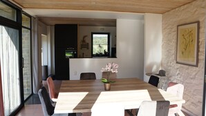 A modern dining area with a wooden table, chairs, and a potted orchid. - Charming house in the countryside (Havelange)