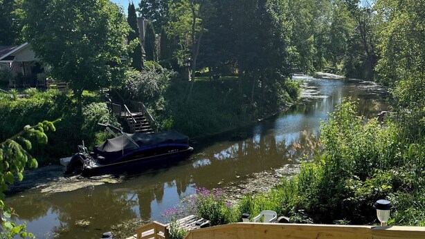 A wooden bridge leading to a river with a boat docked on the left.