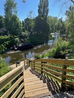 Un puente de madera que conduce a un río con una barca amarrada a la izquierda.
