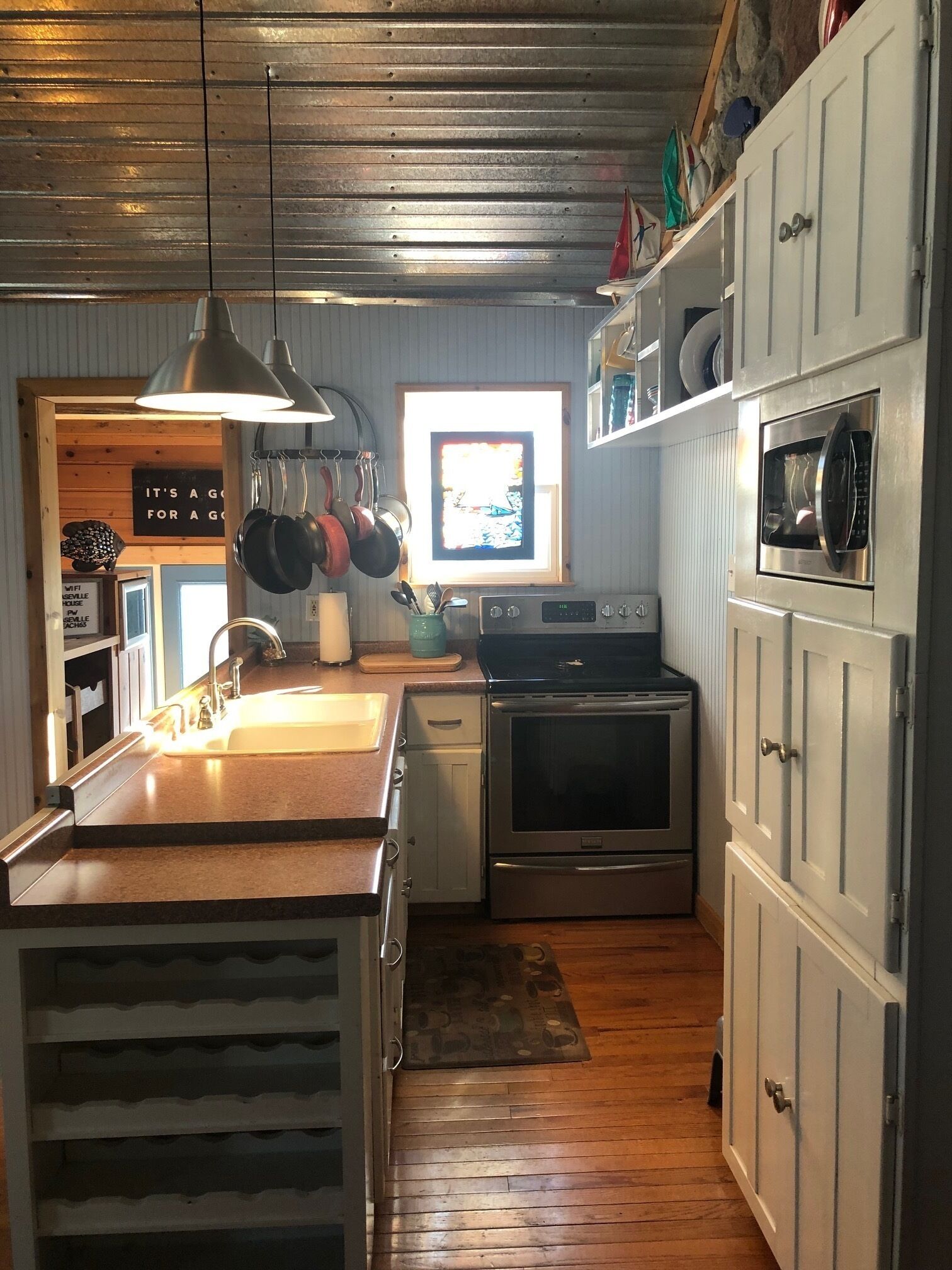 A kitchen with a wooden countertop, stainless steel appliances, and a hanging pot rack.