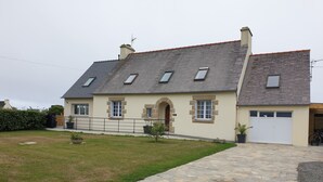 Une maison à deux étages avec une allée pavée de pierres, un petit jardin et un garage.
