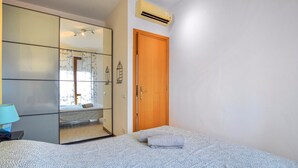 Un dormitorio con cama, armario, puerta y equipo de aire acondicionado.