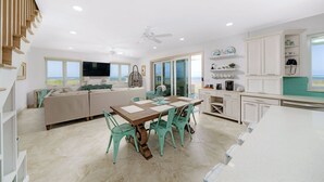 Une cuisine moderne avec un coin repas, des meubles blancs et une vue sur l’extérieur.