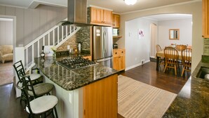 A kitchen with granite countertops, stainless steel appliances, wooden cabinets, and a dining area with chairs and a table. - Lovely spacious 6 BR home in St. Croix River valley (Taylors Falls)