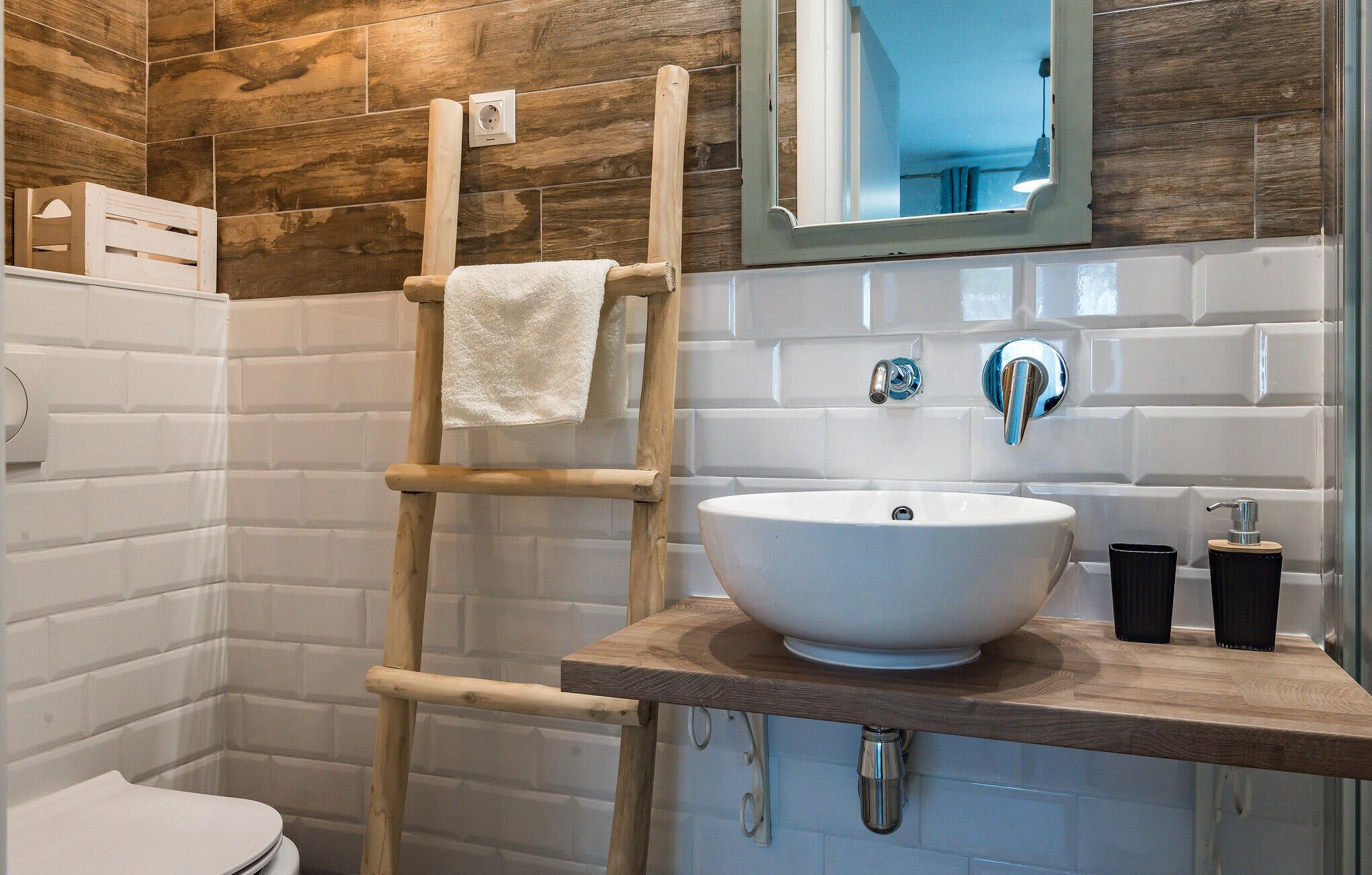 A bathroom with a wooden ladder, a white sink, a mirror, and a toilet.