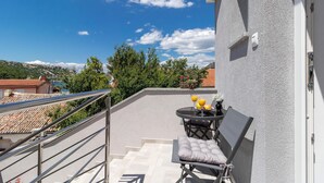 Un balcon avec une table et des chaises, une vue sur les environs et une balustrade.
