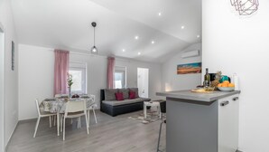 Un espace de vie moderne comprenant un coin repas, un canapé, un îlot de cuisine et un luminaire suspendu au plafond.