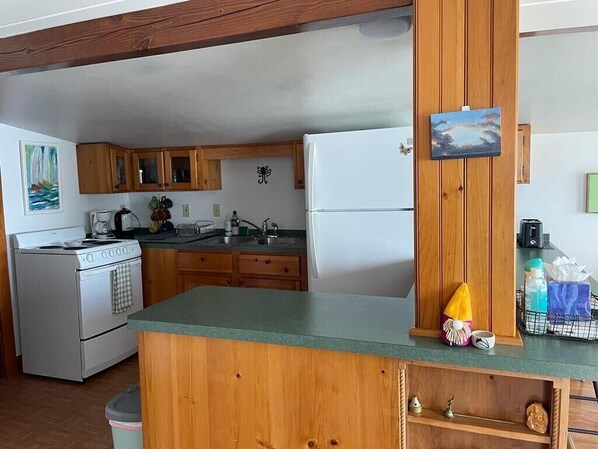 A compact kitchen with wooden cabinets, a white refrigerator, and a small island counter. - Wonderful water front house (Buzzard Bay)