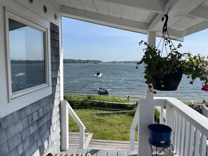 A wooden deck with a view of a lake, boats, and a hanging plant. - Wonderful water front house (Buzzard Bay)