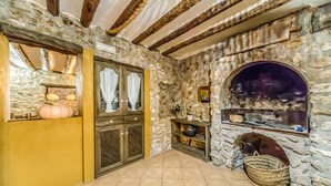 Un intérieur rustique en pierre, avec un four en pierre, des poutres en bois et un mur jaune.