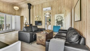 A cozy living room with a fireplace, leather sofas, a wooden coffee table, and a television.