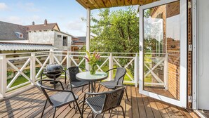 Una terrazza esterna con pavimento in legno, un tavolo rotondo e quattro sedie.
