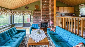 A cozy living room with blue sofas, a fireplace, and a kitchen area with wooden cabinets.