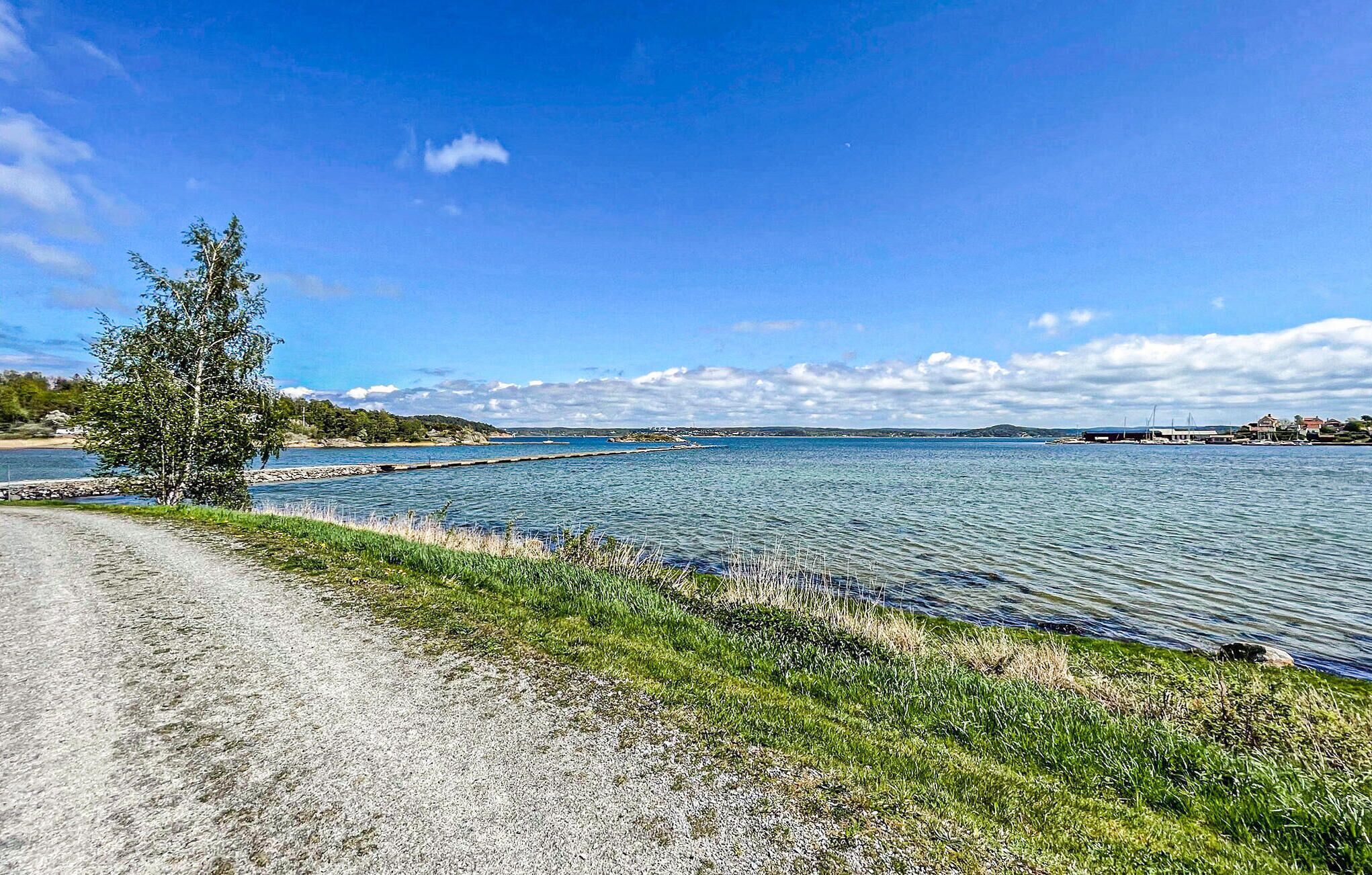 A coastal road with a clear view of the sea and distant hills.