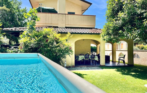 A swimming pool, outdoor seating area, and a building with a tiled roof.