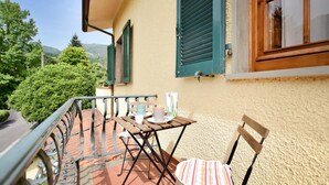 Ein Balkon mit Tisch, Stühlen und Blick auf Grünflächen und Hügel.