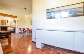 Un vaste espace de vie doté d’une cheminée, d’une table à manger avec des chaises et d’une grande fenêtre offrant une vue sur la mer.