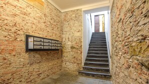 Uma escadaria estreita com paredes de pedra e corrimão de metal.