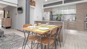 A modern kitchen with a dining area, featuring a wooden table, chairs, and a kitchen island with appliances.