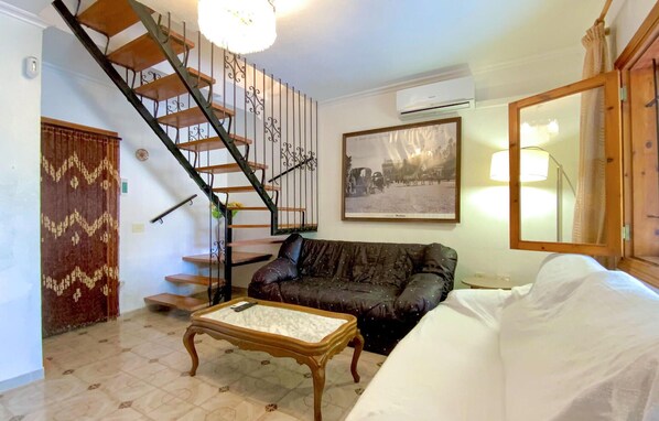 A living room with a staircase, a sofa, a coffee table, a framed picture, and an air conditioning unit. - Pet friendly home in Los Alcázares with WiFi (Los Alcázares)