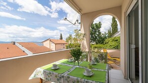 Ein Balkon mit Tisch für zwei Personen, einer Satellitenschüssel und Blick auf die Nachbarschaft.