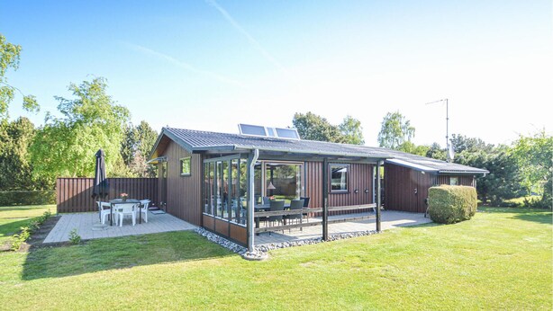 A modern house with a covered patio, solar panels, and a fenced yard.