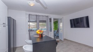 Een moderne keuken met een inbouwkoelkast, een wit toilet en een eethoek met een tafel en stoelen.