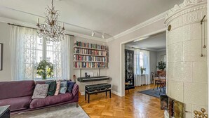 A spacious living room with a purple sofa, a bookshelf, a piano, and a fireplace. - Amazing home in Göteborg with WiFi (Göteborg)