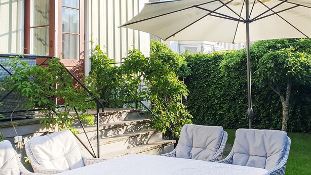 A patio with a table and chairs, a large umbrella, and a hedge in the background. - Amazing home in Göteborg with WiFi (Göteborg)