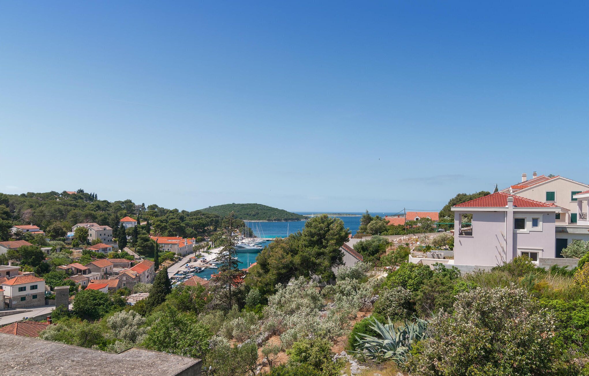 Une ville côtière dotée d’un port de plaisance, d’immeubles résidentiels et d’une colline couverte d’une végétation luxuriante.