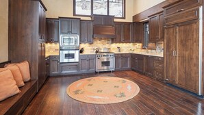 A kitchen with dark wooden cabinets, stainless steel appliances, a large window, and a round rug on the floor. - Stay on Forest Road! Walk to Lionshead! (Vail)