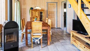 Ein gemütliches Zimmer mit einem Holzesstisch, Stühlen, einem Kamin und einem Fernseher auf einem Holzboden.