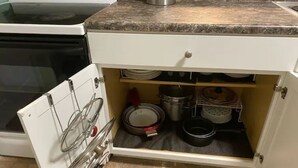 Eine Küche mit einem weißen Schrank, der verschiedene Küchenutensilien und Kochgeschirr beherbergt.