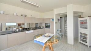 Une cuisine moderne dotée d’un îlot central, d’une table à manger et d’un meuble vitré.