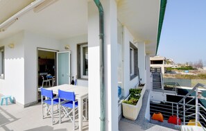 Un balcon avec une table et des chaises, un escalier et une vue sur les environs.