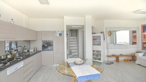 Une cuisine moderne équipée d’une cuisinière à gaz, d’un four et d’une table à manger en verre recouverte d’une nappe bleue.