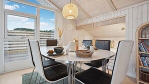 Un coin repas avec une table ronde, des chaises noires, un panier en osier et un luminaire suspendu.