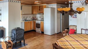 Una cocina con armarios de madera, estufa, refrigerador y una mesa de comedor con sillas.