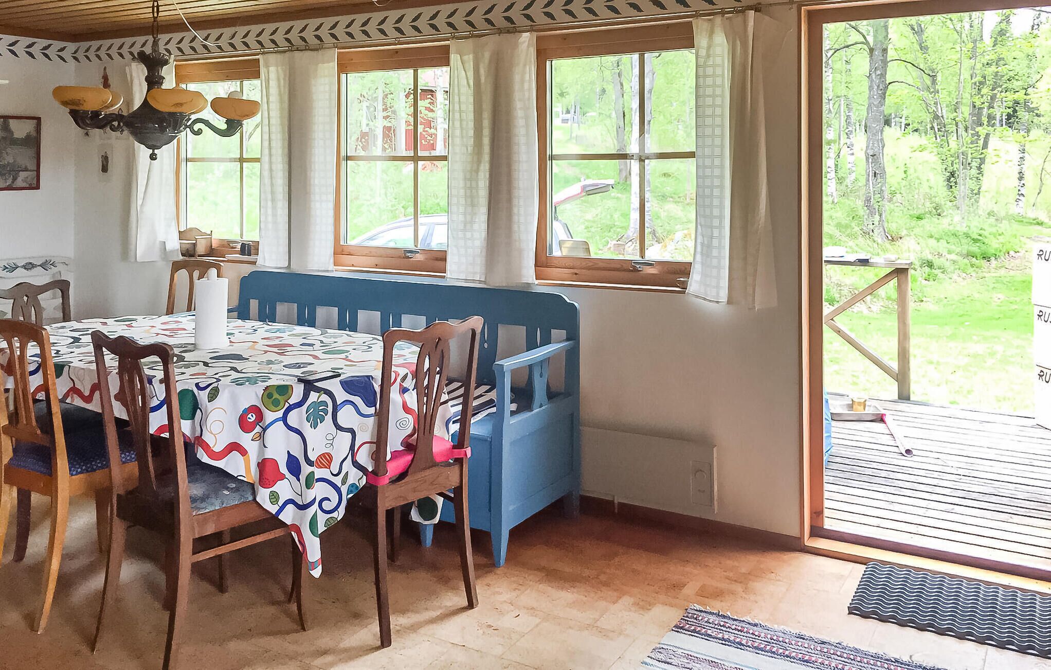 A dining area with a table set for four, a blue bench, and large windows offering a view of the outdoors.