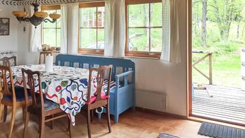 A dining area with a table set for four, a blue bench, and large windows offering a view of the outdoors.
